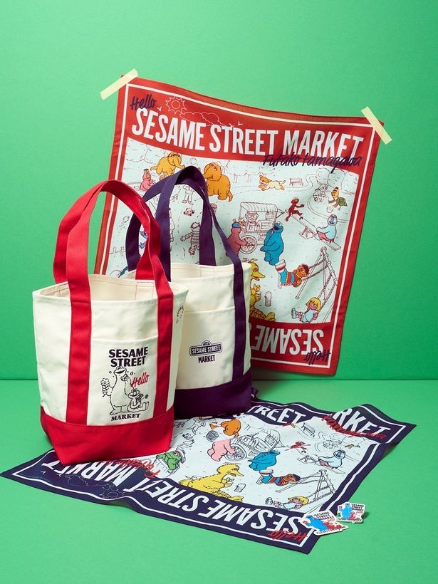 トートバッグ、バンダナはレッドとネイビーの2色展開。手前にはピンバッジとステッカーも