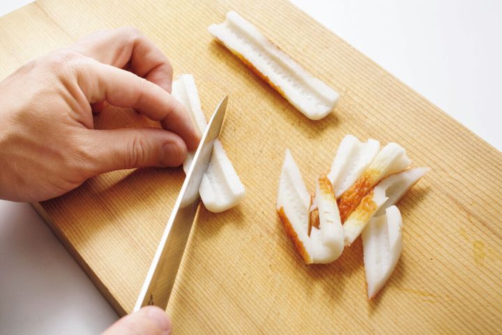 まな板の上でちくわを斜め切りにしている