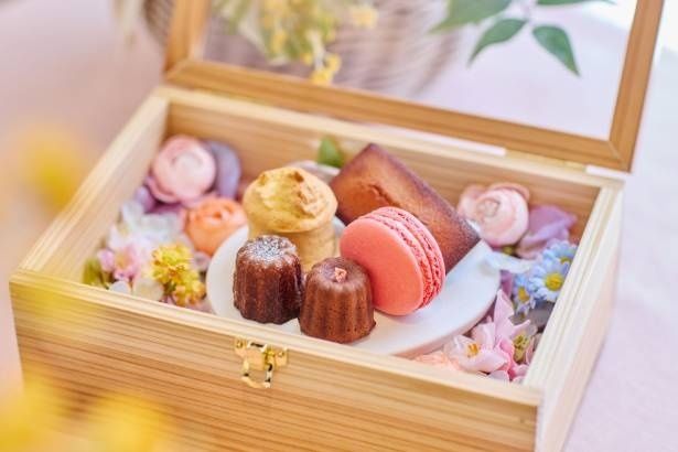 花々に囲まれたスイーツボックス。マカロンやオリジナルカヌレがそろい、春の小樽を表現した華やかなアフタヌーンティーセット