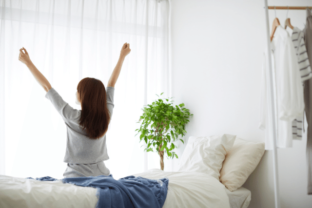 ベッドの上で伸びをする女性