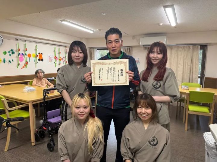 感謝状を手にした男性とスタッフ4人の記念写真