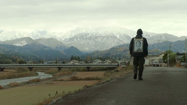 【写真】妻・明希(山谷花純)の遺影をアピールしながら歩く浅岡(成田凌） (C)2026 #VIRAL PRODUCTION COMMITTEE