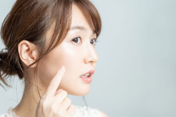 頬を指さす女性