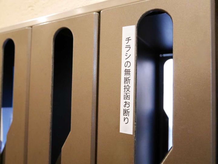 「チラシの無断投函お断り」ステッカーが貼られた集合郵便受けのアップ