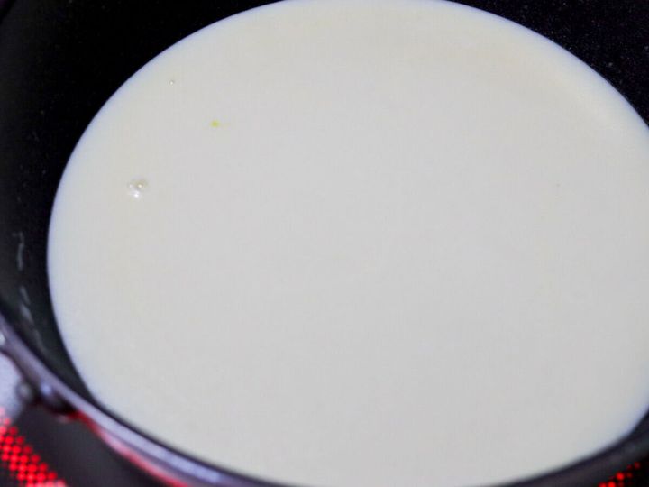 フライパンに牛乳を加えた白いソースを加熱している様子