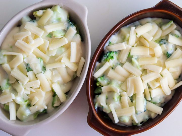 2つの耐熱グラタン皿にブロッコリーとクリームソースを入れてピザ用チーズをのせた焼く前の状態