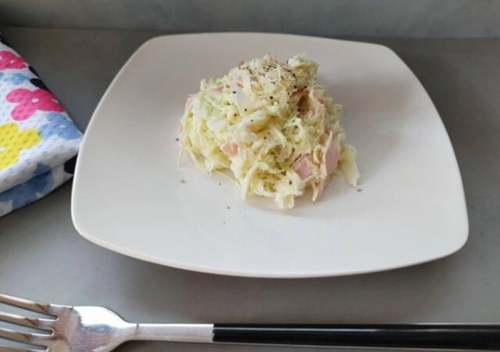 白い四角いお皿に盛られたコールスロー。黒こしょうが散りばめられフォークと箸が添えられている