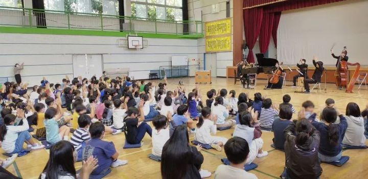 スクールコンサートで手を挙げて参加する児童たち