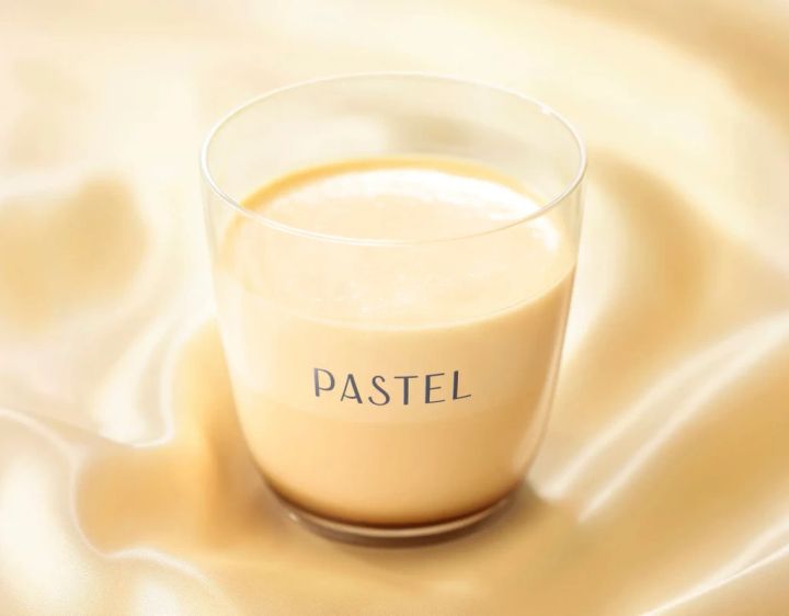 パステル色の液体が入ったグラスが、光沢のある布の上に置かれています。