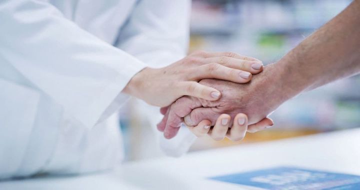 患者の手を握る薬剤師