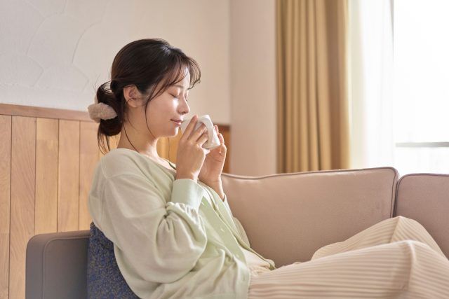 朝、あたたかい飲み物を飲む女性