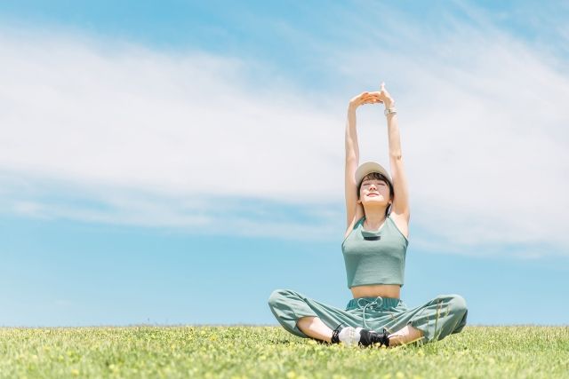 芝生の上でストレッチする女性