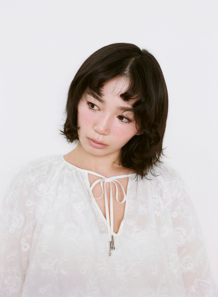 白いレースドレスを着て伏し目がちなポーズをとる宮﨑優。