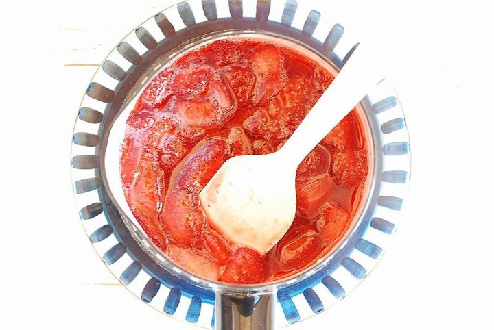 ガスコンロ上の鍋でいちごソースを木ベラで混ぜながら加熱している俯瞰写真