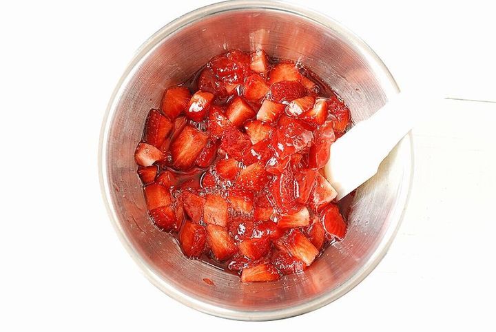 ステンレスボウルに生の角切りいちごと煮たいちごソースをゴムベラで混ぜ合わせている俯瞰写真