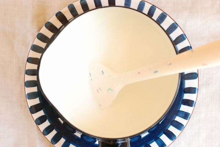 小鍋に牛乳と生クリームと砂糖を入れゴムベラで混ぜている俯瞰写真