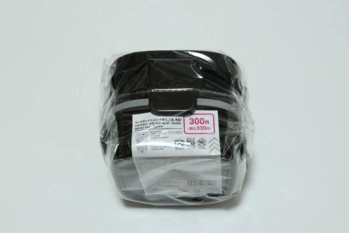 透明袋に入った黒い2段弁当箱と330円税込の値札