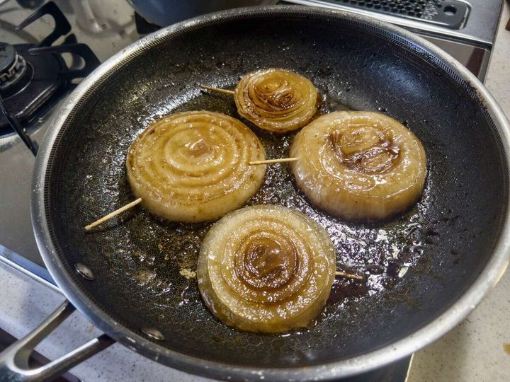 フライパンでバターをからめて照りが出た輪切り新玉ねぎに醤油を仕上げに加えている工程の俯瞰写真