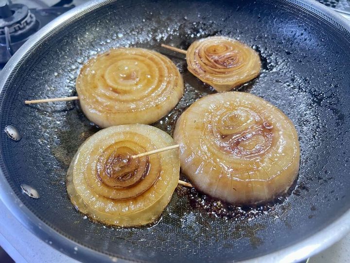 フライパンで両面に焼き色をつけた輪切り新玉ねぎに白ワインビネガーを回しかけている工程の俯瞰写真