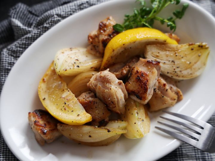 白い皿に盛った鶏もも肉と新玉ねぎのレモンペッパー炒めにパセリを添えた完成品