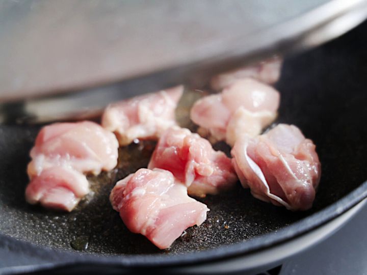 フライパンに鶏もも肉を皮目を下にして並べ蓋をして中弱火で焼いている工程の写真