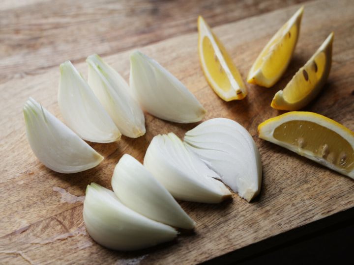 まな板に8等分にカットした新玉ねぎと4等分の串切りレモンを並べた下準備の写真