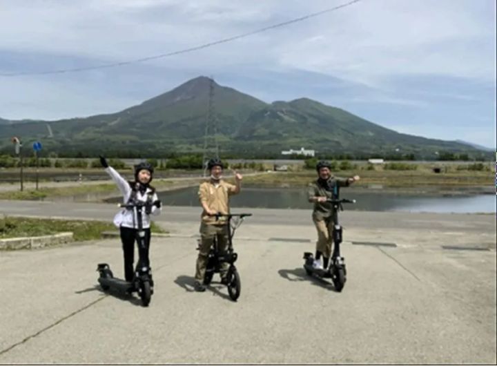 磐梯山を背景に電動キックボードを走らせる