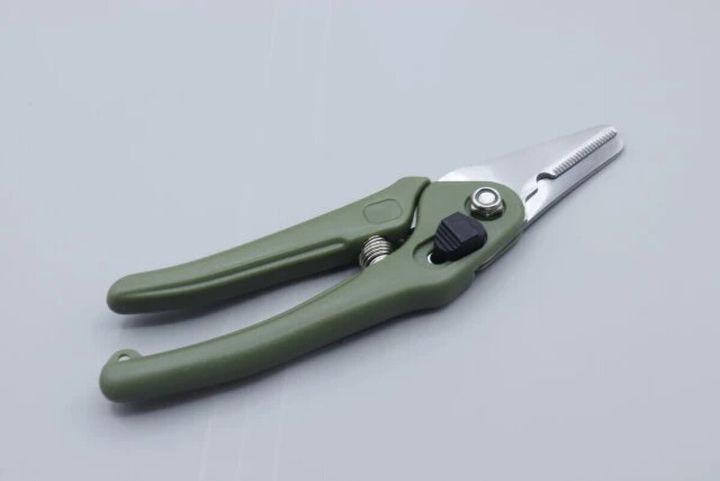 グリーンのグリップと銀色の刃のダイソー園芸万能ハサミが開いた状態で置かれている