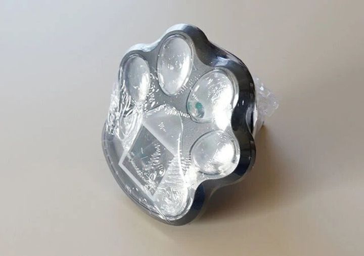 猫の肉球型をしたシルバーのソーラーガーデンライトが袋に包まれた状態で置かれている