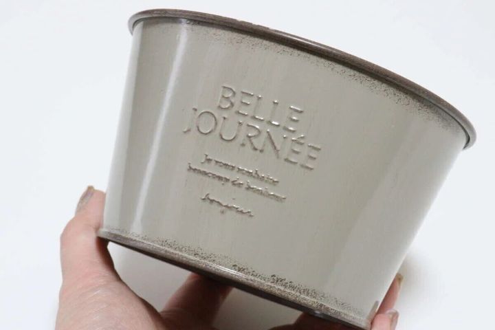 女性がグレーのヴィンテージ風アイアンポットを片手で持ち上げておりBELLE JOURNEEの刻印がある