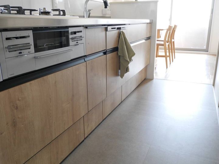 キッチンマットなしで白い床タイルがすっきりと見える木目調キャビネット前の様子