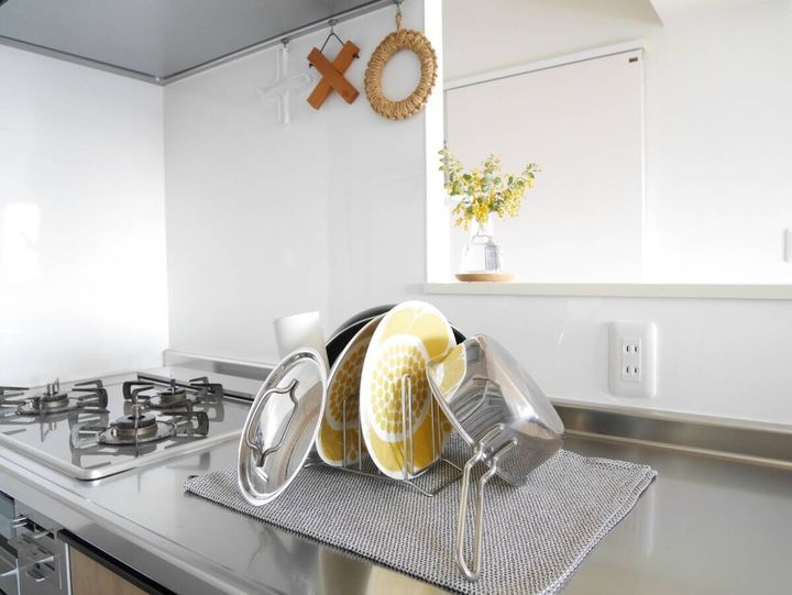 白いキッチンのカウンターにティータオルを敷いてスタンドにお皿や鍋蓋を立てかけたすっきりとした水切りの様子