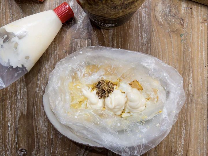 アイラップ内のスクランブル状の卵にマヨネーズと粒マスタードを加えている俯瞰写真