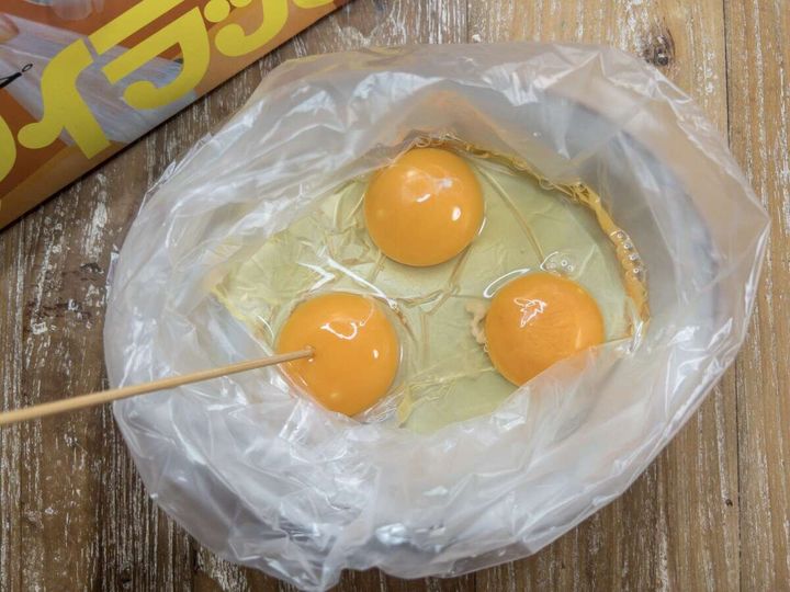 アイラップに割り入れた卵3個の卵黄に竹串で穴を開けている俯瞰写真