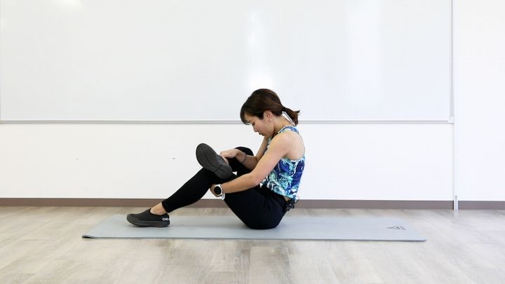 座り4の字ストレッチのやり方1 体育座りになり、片足をもう片方の膝にのせて背中を丸める