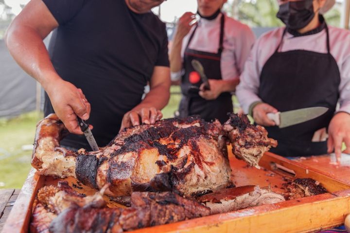 伝統的な屋外バーベキューで、炭火の余熱を使い丸ごとの豚をじっくり焼いている