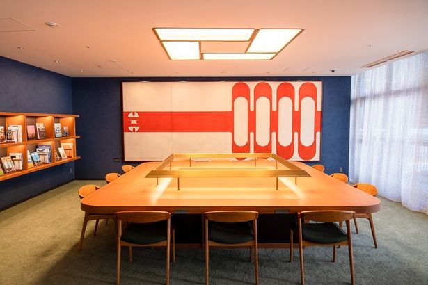 横浜にまつわる本が集められた「ライブラリーラウンジ」。壁には、かつて市民広間の2階に飾られていた、佐藤亜土さんによるアートワークが展示されている