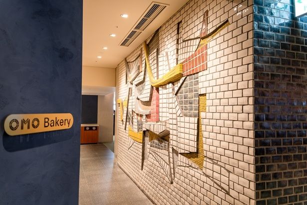 彫刻家・辻晋堂さんの作品「海・波・船」は、当時の位置のままOMOベーカリーの壁面として残された