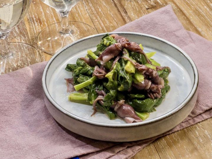 白いプレートに菜の花とホタルイカのマリネが盛り付けられワイングラスを添えた完成品写真