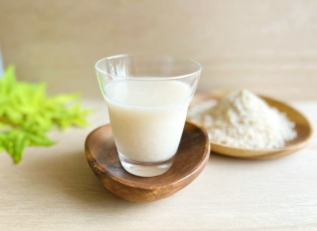 コップに入った甘酒と、背後に米麹