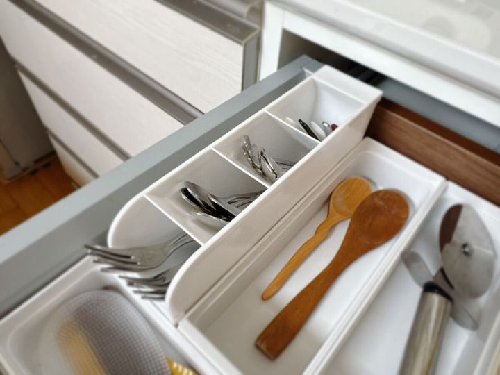 キッチンの引き出しに白いスタンドを横向きに寝かせスプーンやフォークが仕切りごとに収納されている