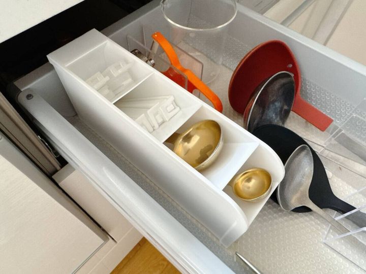キッチンの引き出しに白いスタンドを横置きし計量スプーンや食品クリップが仕切りごとに収納されている俯瞰写真