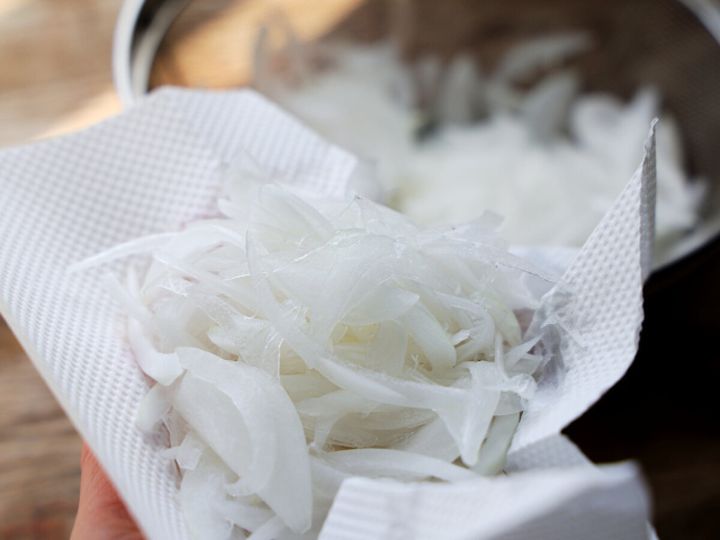 キッチンペーパーで水気を切った新玉ねぎスライスを手で持っている様子