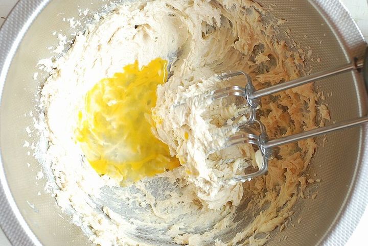 バターと砂糖の生地に溶き卵を加えて泡立て器で混ぜている様子