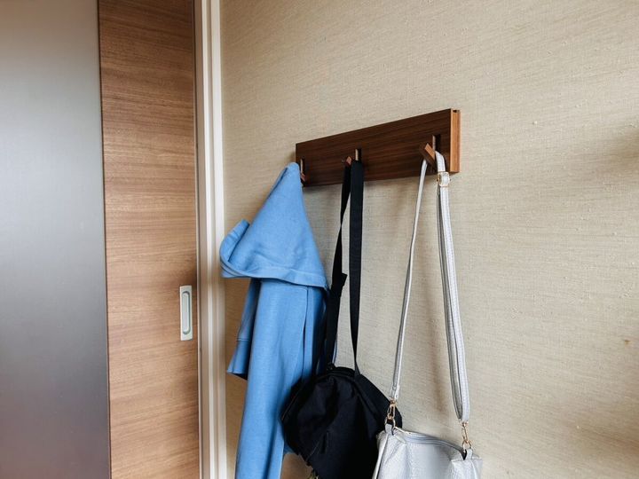 壁の木製フックにパーカーやバッグを掛けた玄関収納
