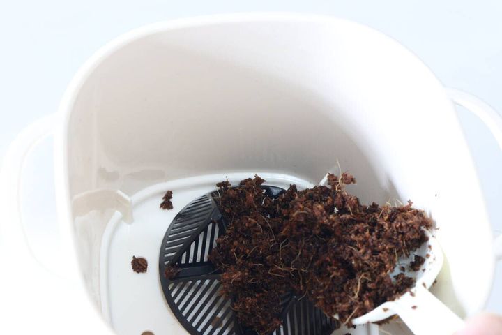 ダイソーのバスケットポット3号 アイボリーに鉢底ネットと土を入れる様子