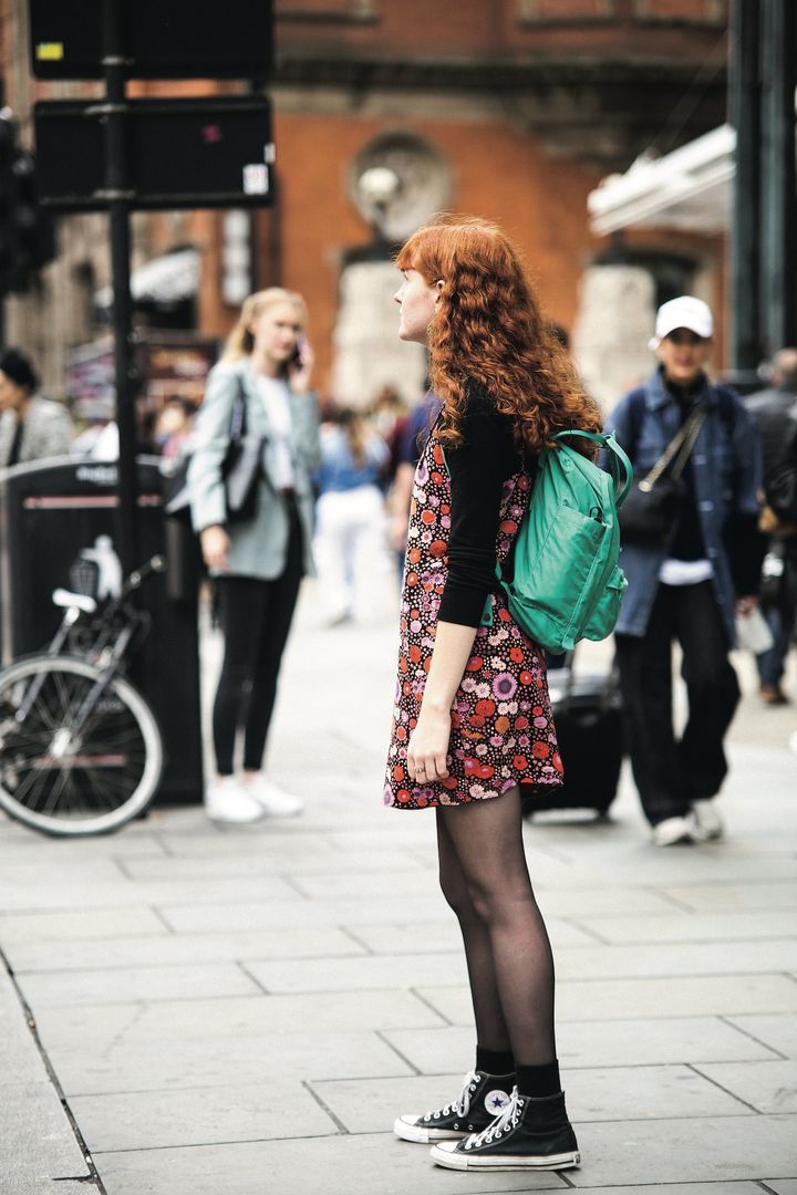 ブラックベースのコーデに花柄のワンピースにグリーンのリュックを合わせて季節感を演出