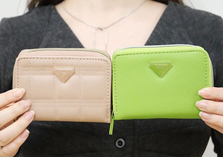 女性がピンクとアップルグリーンの2色のやみつきサイフを両手に持って見せている様子