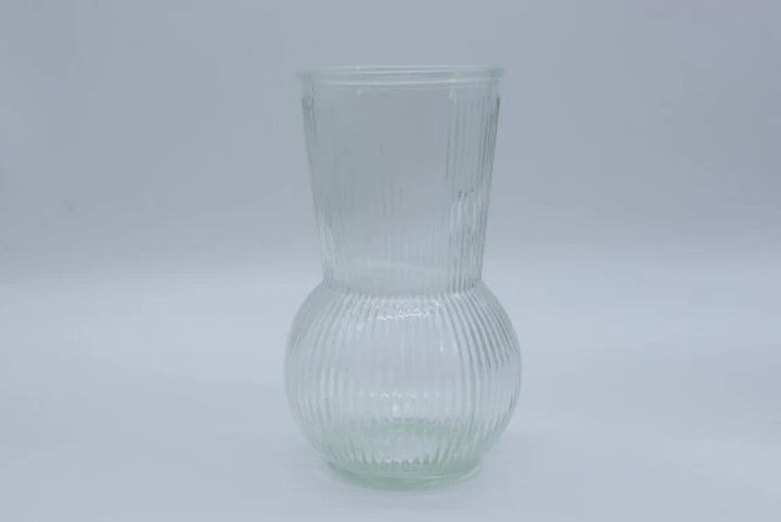 縦リブ模様の透明なガラスフラワーベースが白い背景に置かれている