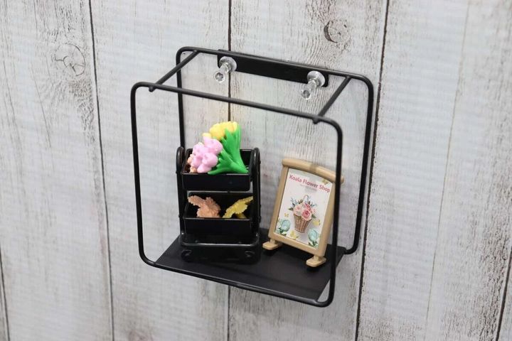 黒いアイアン壁掛け収納が木目調の白い壁に取り付けられミニチュア雑貨が飾られている